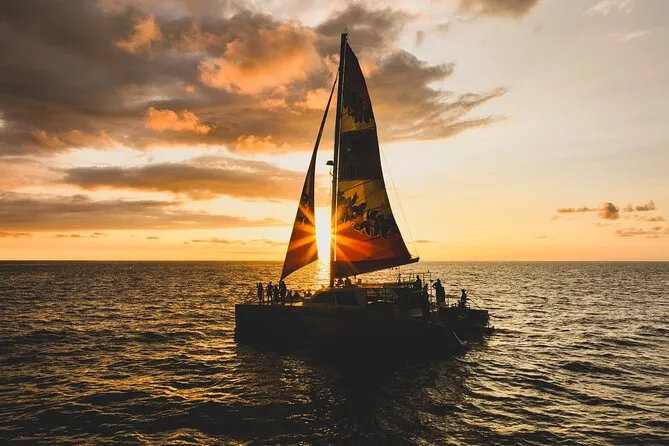 Passengers aboard a sailing catamaran watching the golden sunset over the Pacific on a kona sunset cruise from Honokohau Harbor, Big Island Hawaii