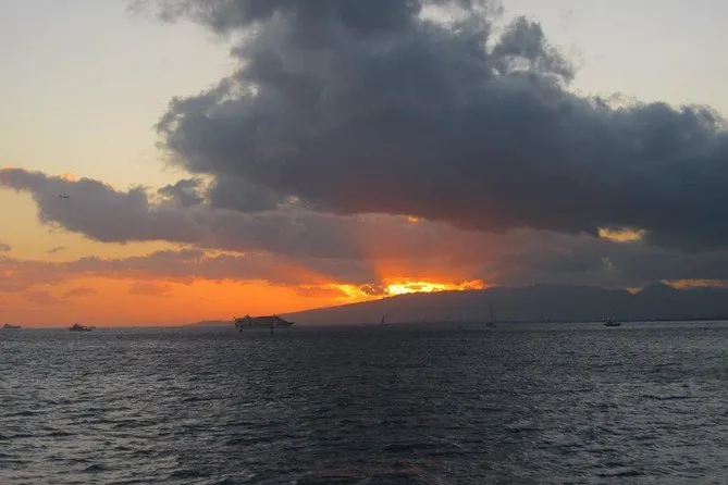 A large sailing catamaran cruising the Kohala-Kona coastline at golden hour on a kona sunset cruise from Waikoloa, Big Island Hawaii