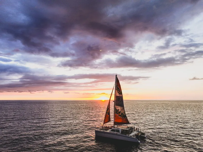 Guests relaxing on the deck of the Spirit of Aloha catamaran with tropical cocktails on a kona sunset cruise from Honokohau Harbor, Big Island Hawaii